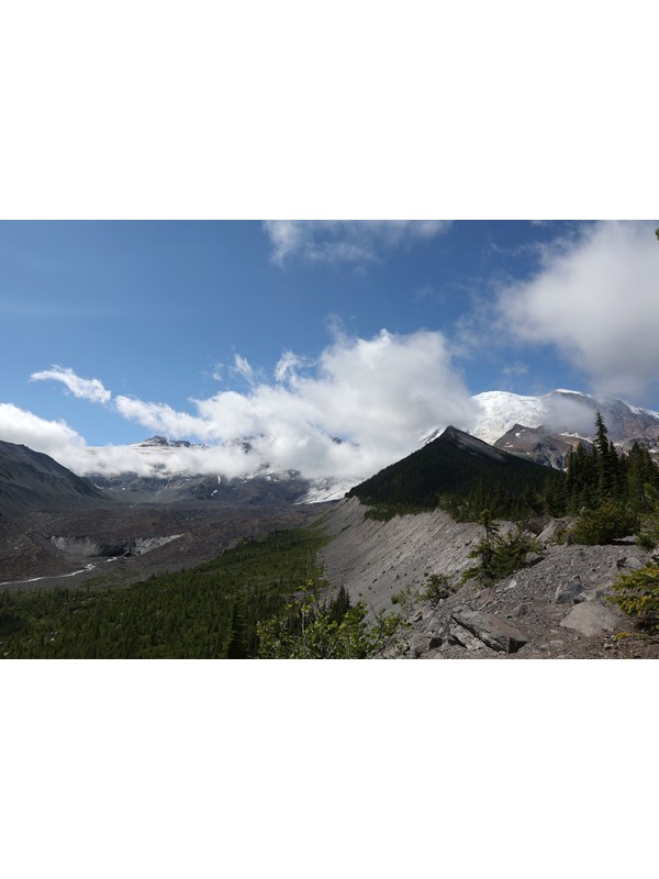 View of mountain with rocky glacier moraine with clouds partially covering glacier