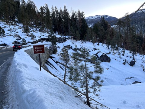 A snowy landscape of a road going over a creek.