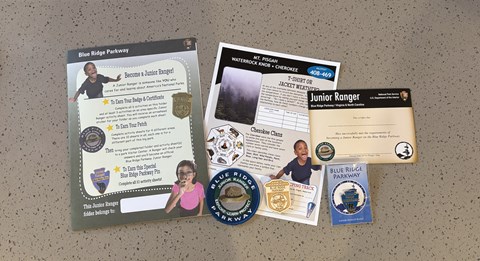 color photograph of the junior ranger activity sheets and wooden badge and fabric patch