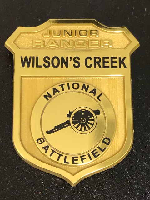 Plastic Junior Ranger badge with Wilson's Creek National Battlefield on it and a cannon emblem