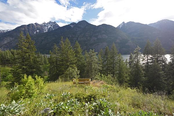 A wooden bech overlooks a wide wide of surrounding hills