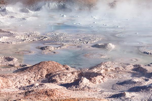 Steam rises from bubbling mudpots in a thermal basin.