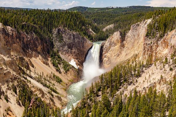 A waterfall cascades over a cliff in a canyon with pale colored walls.