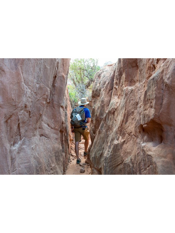 hiker with permit in narrow path between tall rock walls