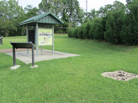 Free standing exhibits and wayside panels are located on the grassy lawn of the site of the market.