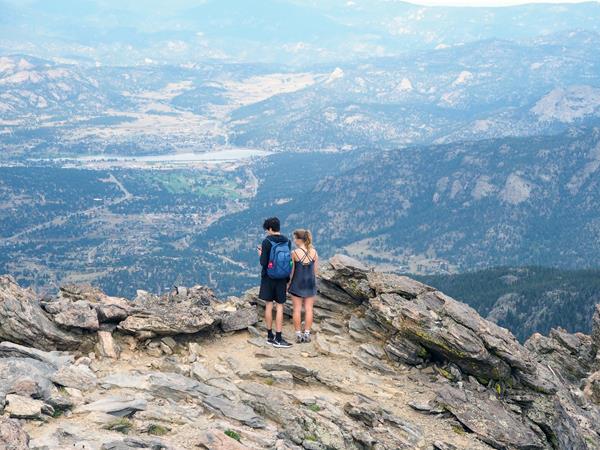 two people standing on a mountain top taking in the view