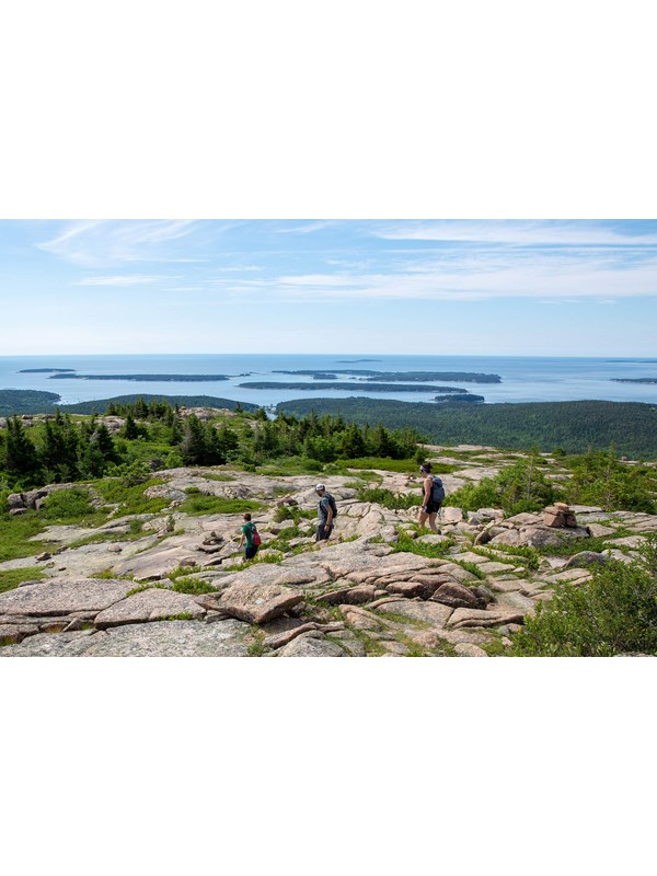 Blue skies above Jordan Pond with views of tree lined North and South Bubble Mountains.