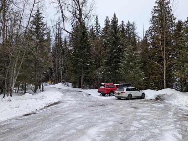 A snow-covered parking lot with two vehicles parked.
