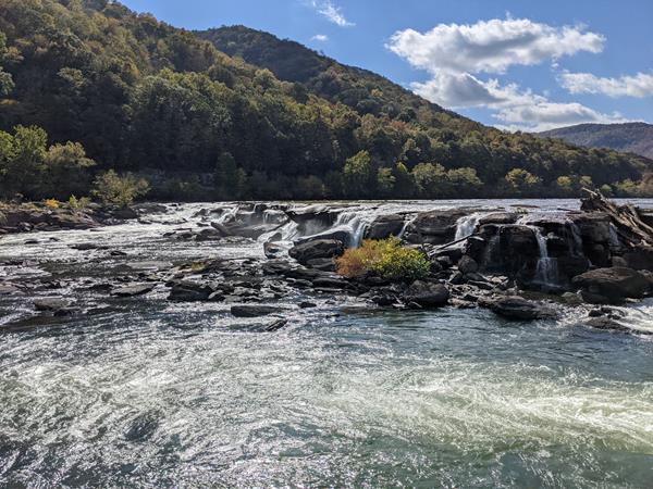 View of the Sandstone Falls with the mountains in the background and the river surging.