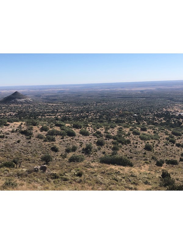 A desert mountain landscape with buildings and a prominent point in the background.