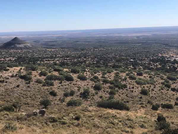 A desert mountain landscape with buildings and a prominent point in the background.