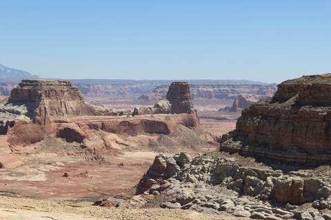 Sandstone cliffs, buttes, and mesas. Just a bit of a lake in the distance.