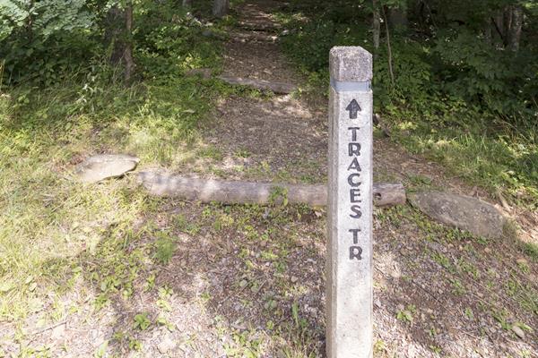 A concrete post at the head of a trail that reads: Traces Trail