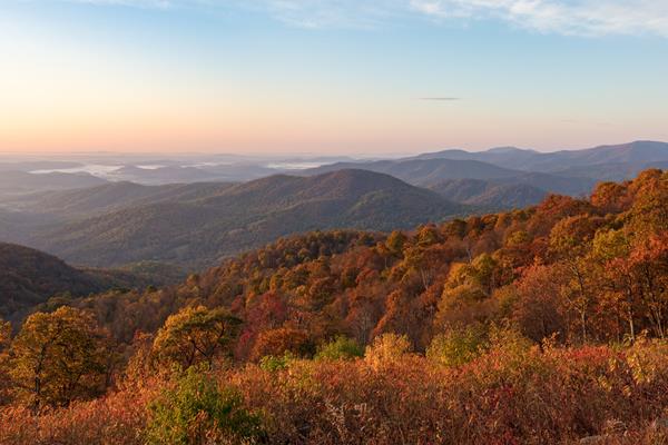 A view from an overlook down into a valley below filled with fall colors of red and orange.