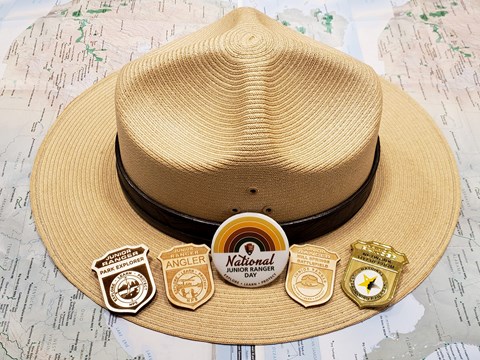 NPS flat hat with 5 Junior Ranger Badges on the brim.