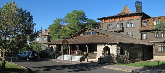 A large, multi-story wooden building features a tall turret and a wide, covered front porch.