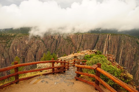 An overlook lined with wooden fencing leading towards a canyon edge