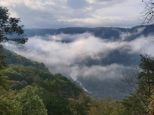 View of the deep gorge filled with clouds. A river is seen at the bottom peeking from the clouds