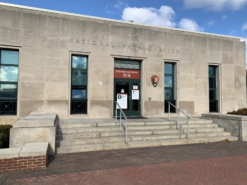 The Information Center on Liberty Island is a concrete building with a few steps leading up to it.