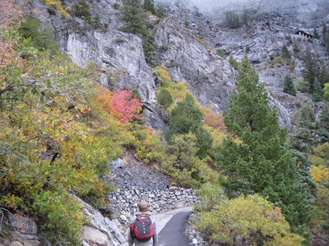 Young boy walking up trail with backpack and jacket