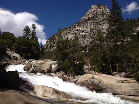 A cascading waterfall with massive granite mountains in the background.