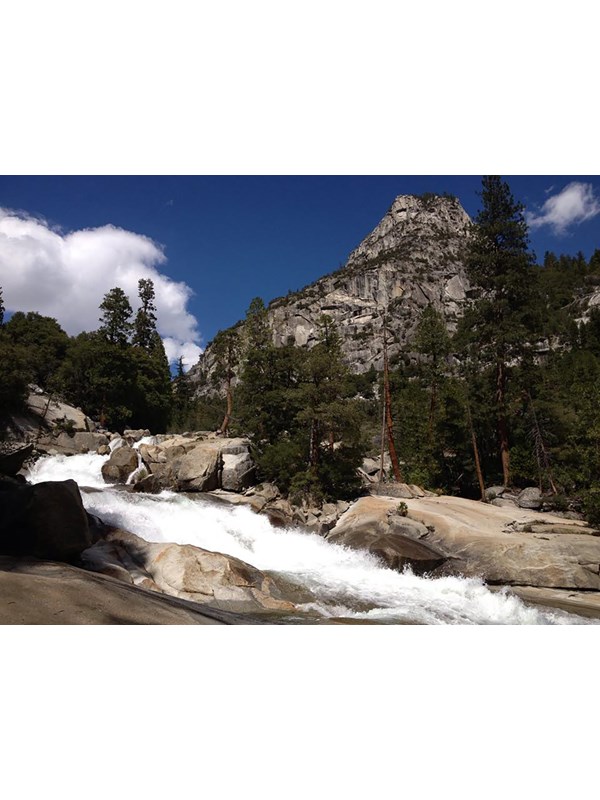 A cascading waterfall with massive granite mountains in the background.