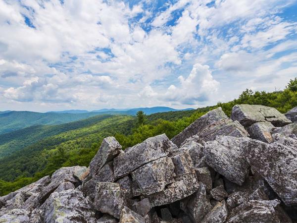 A color photograph of a rocky talus slope facing out to lush green mountains in the distance.