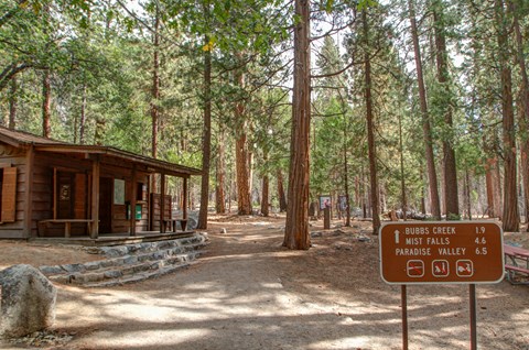 A ranger station next to a trail leading into a forest.