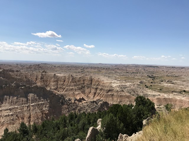 Layered, jagged badlands rock formations stretching toward prairie in the distance