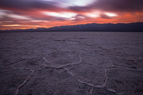 An expansive salt flat with distant desert mountains and a pink sky sunset.