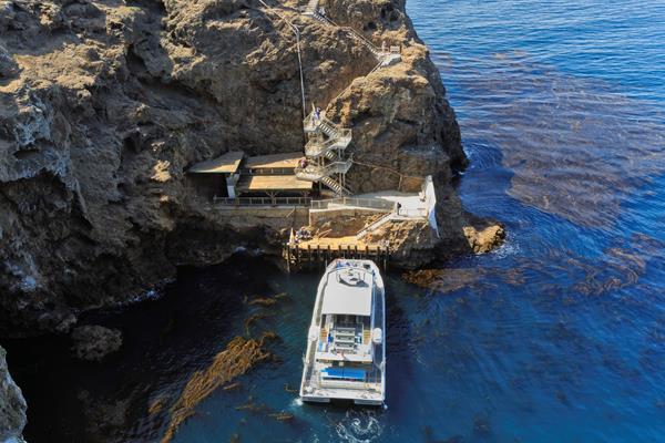 Steep cliff with boat, white sea wall and stairs leading to the top.