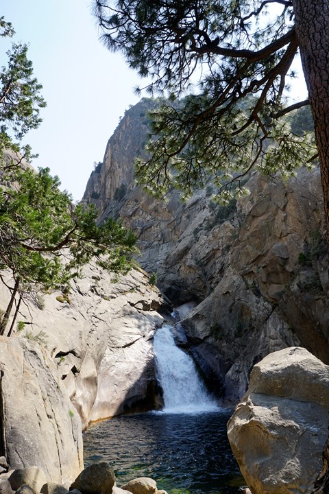 Powerful chute of water pouring into a dark blue pool between high rock walls