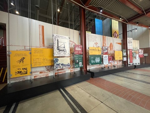 Entryway of museum corridor with exhibit panels suspended from the ceiling