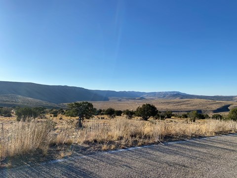 View from a road of a long canyon wall in the desert landscape.