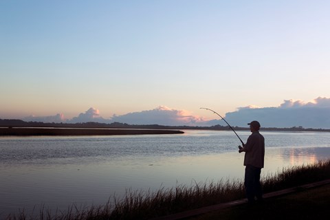 silhouetted angler fishing at dawn