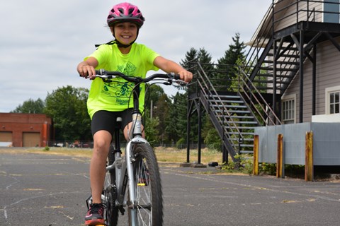 A child on a bicycle wearing a pink helmet.