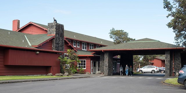Front of a large red wooden building with a driveway and covered entrance