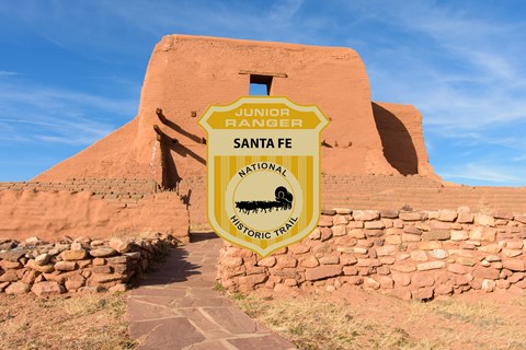 A junior ranger badge over the picture of a ruined adobe mission.
