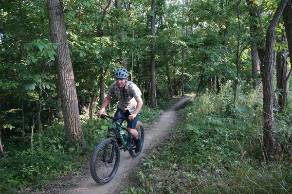 A person wearing a helmet cycles up a mountain bike trail.
