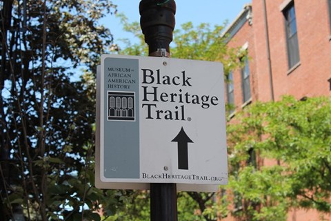 A white square sign on a lamp-post that states "Black Heritage Trail" and has an arrow pointing up.