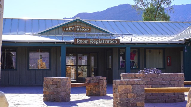 Large single story building with signs reading "Nuggel Gift Shop" and "Hotel Registration".