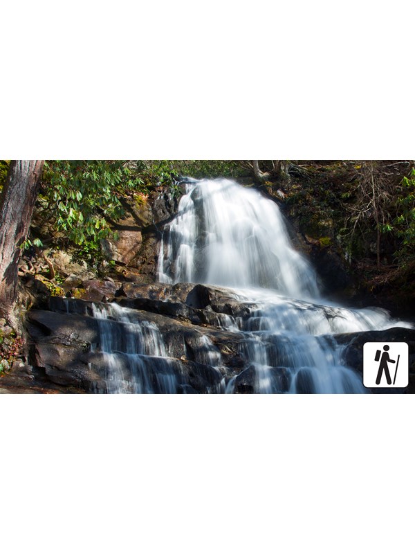 A two-tiered waterfall framed by greenery. Hiker icon in lower right corner.