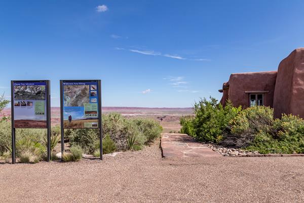 Two signs at the trailhead next to the Pueblo Revival Style inn