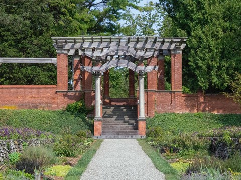 A white marble statue in a red brick pavilion before a reflecting pool.