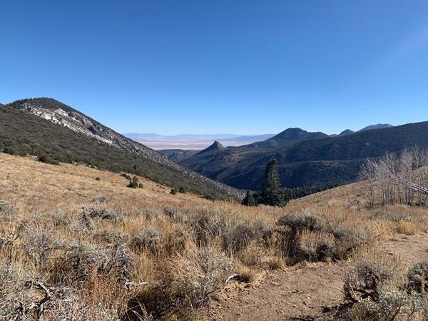 Brown and green sagebrush extends to mountains, a valley behind them, and another distant range.