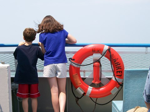 two youth looking at open water from deck of a large boat