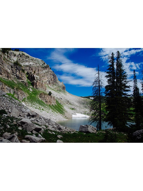 An alpine lake sits at the base of a rocky cliff.