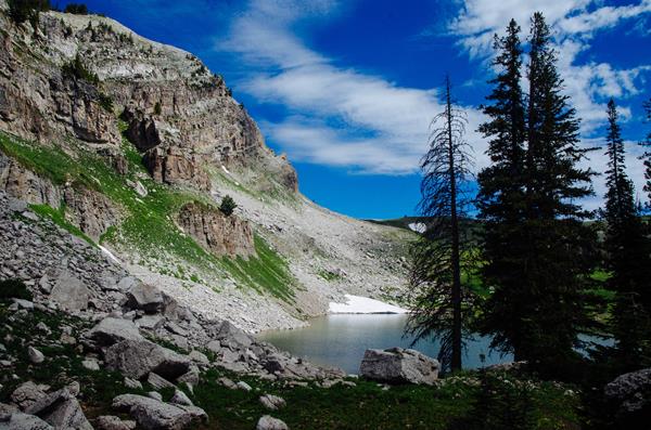 An alpine lake sits at the base of a rocky cliff.