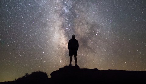 a person standing on a rock silhouetted against the milky way