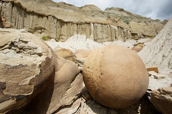 Two large, round stones take up the majority of the image, with more behind, and a butte in the back
